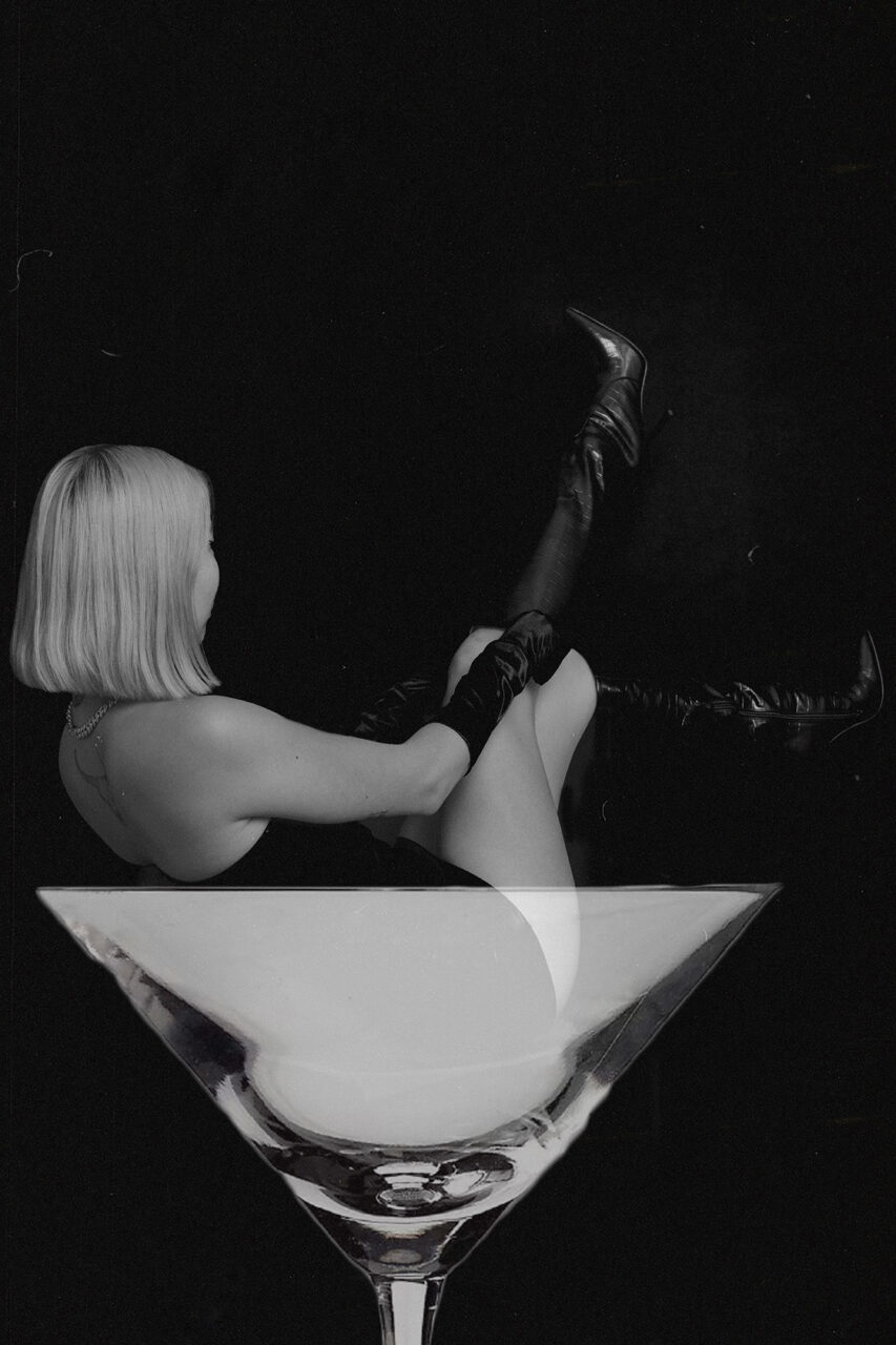 Woman pulling up her boots sat on a champagne glass